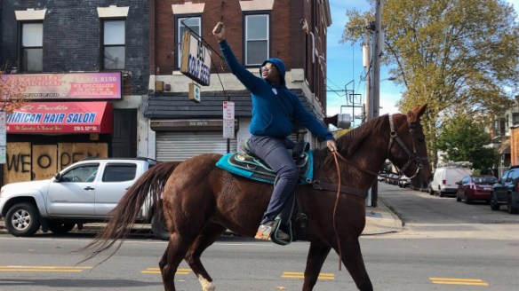 13-year-old Nahye Hyman raises a fist on his horse Sally during a GOTV ride down 52nd Street