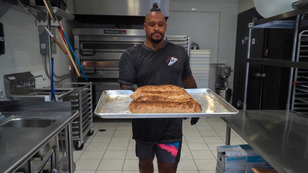 Chef David Lee carries loaves of lard bread at Pizza Jawn